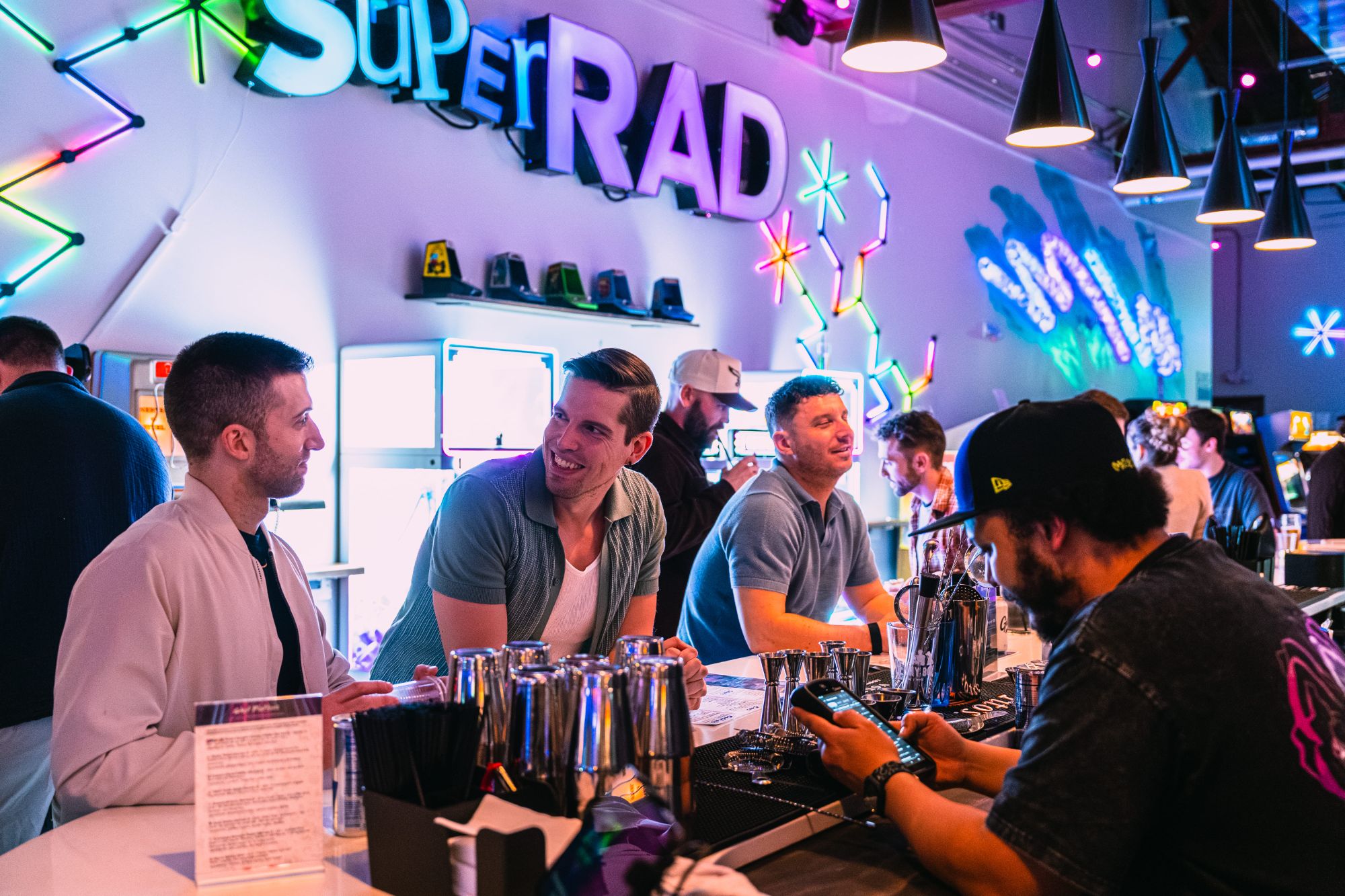 Guests at the bar with Super Rad neon sign Glenwood South
