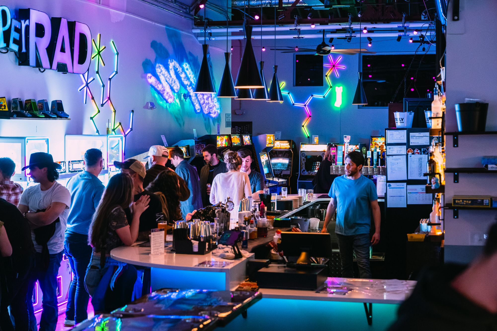 A crowd enjoying drinks at the neon bar at Super Rad Retro Lounge