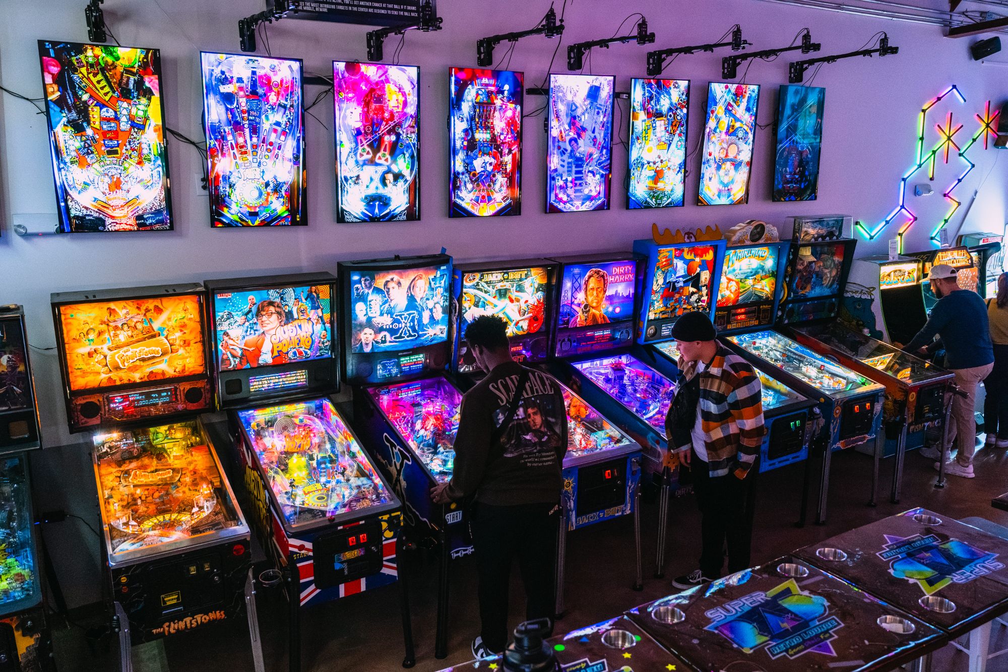 Guests playing a row of restored pinball machines at Super Rad Raleigh