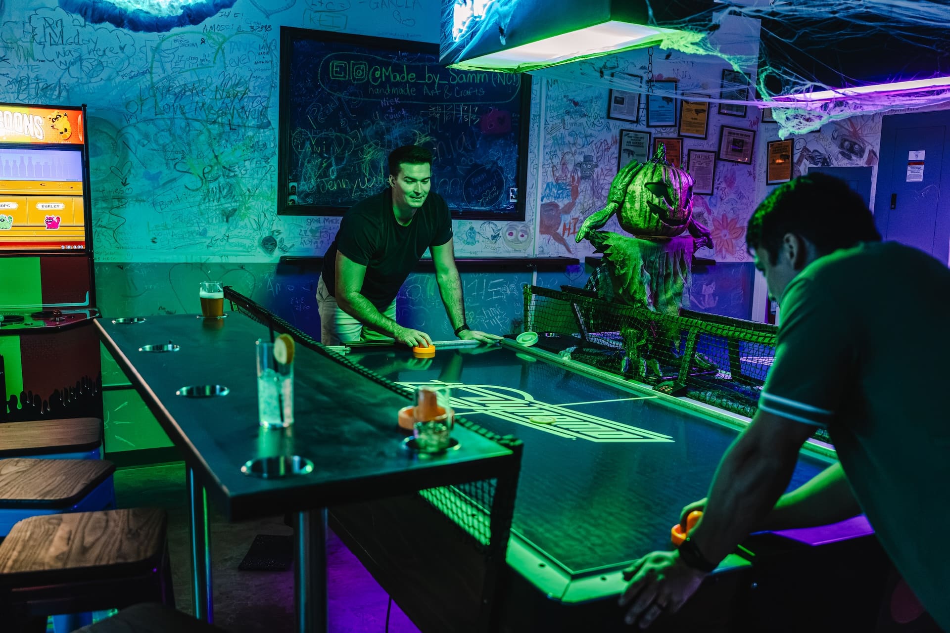 Friends playing air hockey at a Super Rad arcade bar party in Raleigh